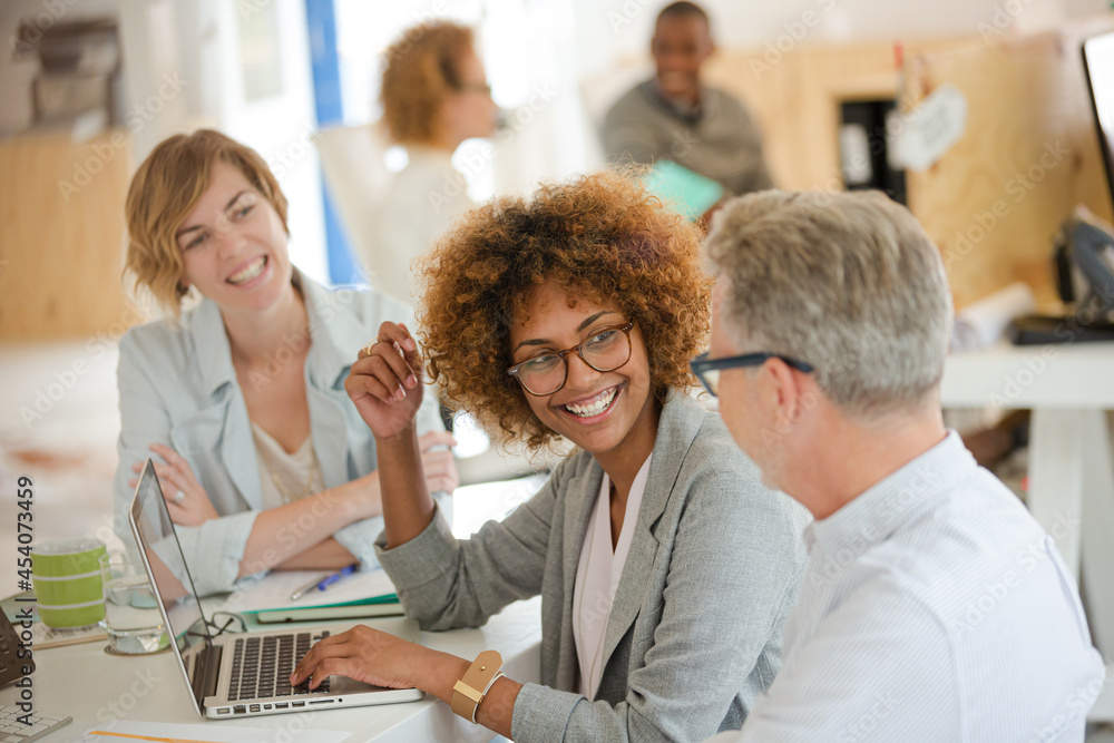 Fototapeta premium Three office workers talking at desk with laptop