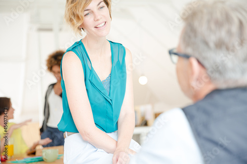 Man and woman sitting in office,smiling and talking