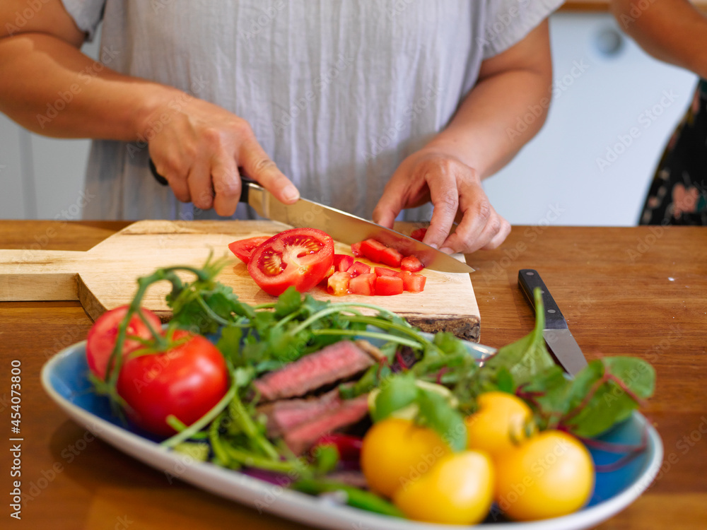 Close-up of woman's hands cutting tomatoes at kitchen counter