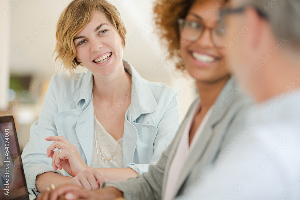 Three office workers talking at desk with laptop Three office workers talking at desk with laptop