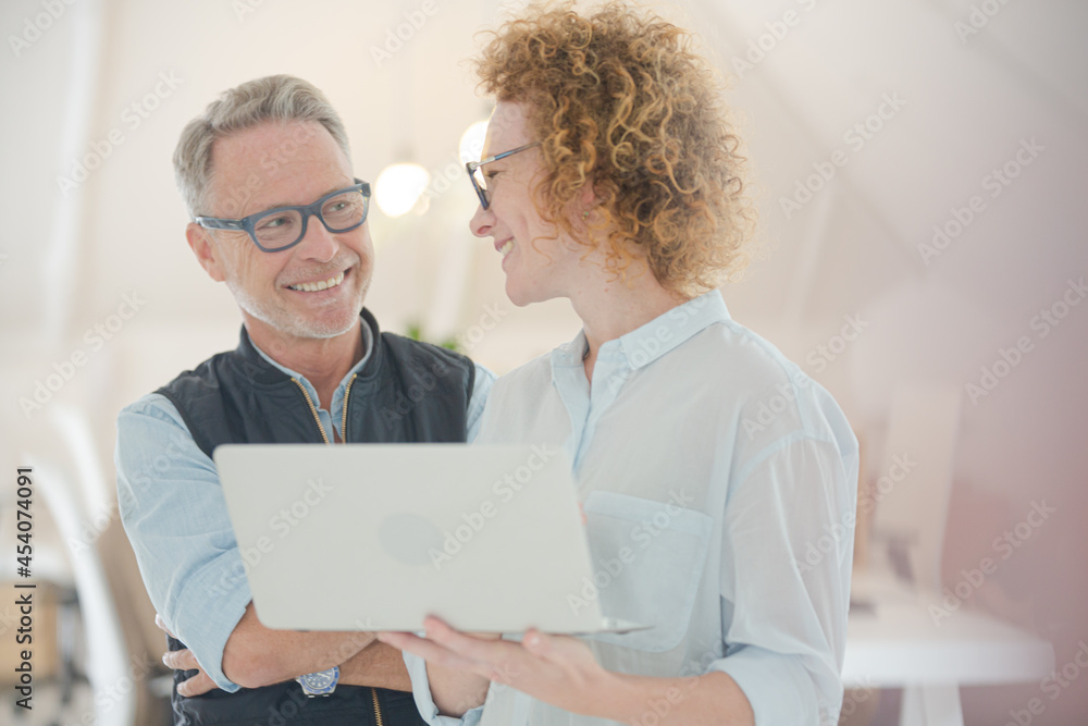 Portrait of man and woman with laptop, smiling in office Portrait of man and woman with laptop, smiling in office