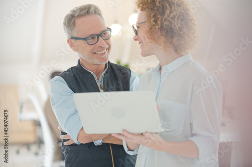 Portrait of man and woman with laptop, smiling in office