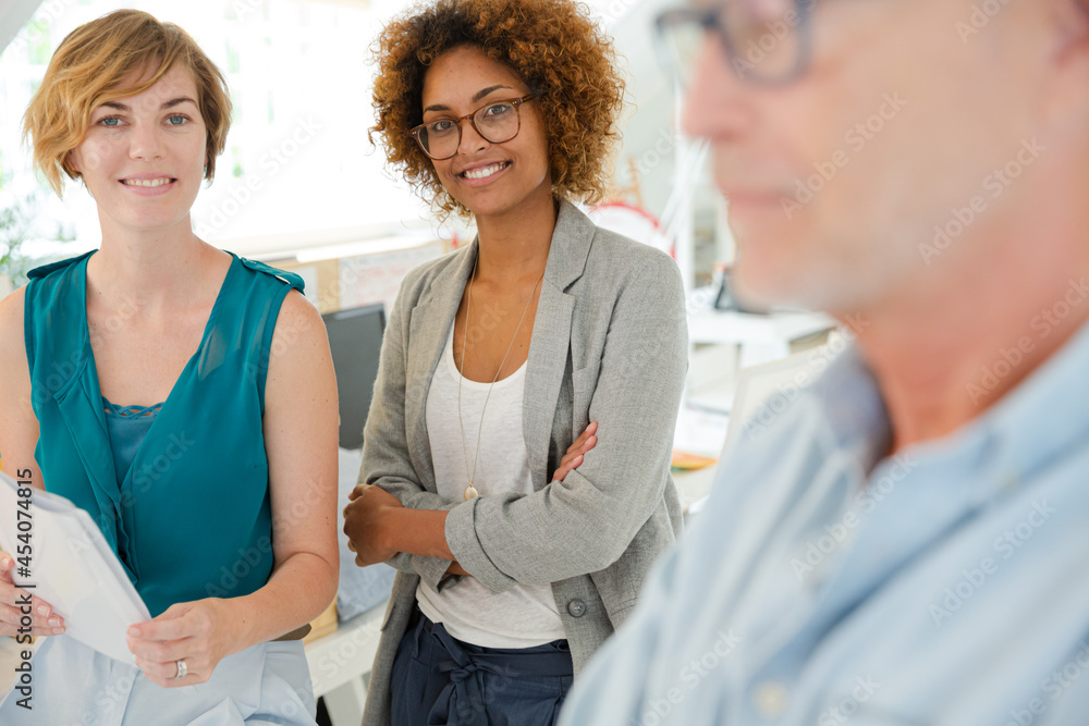Fototapeta premium Colleagues talking and smiling in office, holding documents