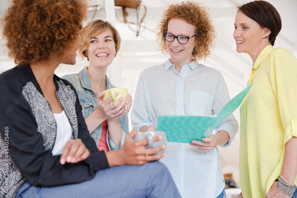 Women with coffe cup talking in office Women with coffe cup talking in office