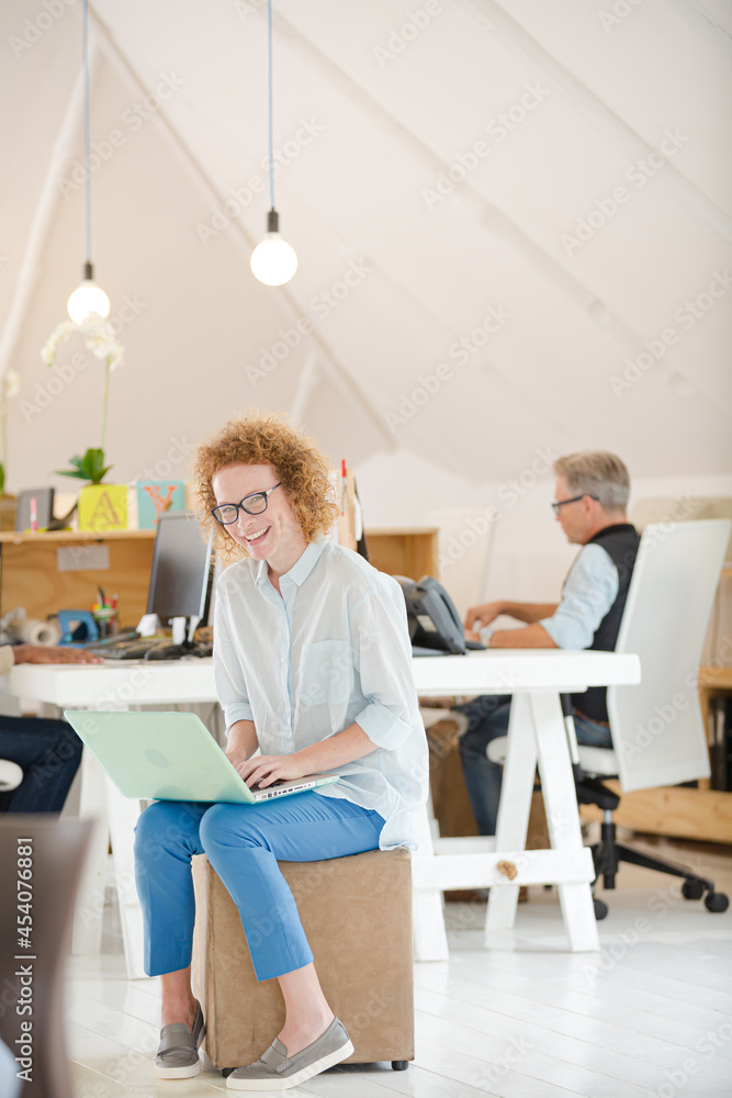 Woman using laptop and smiling in office Woman using laptop and smiling in office