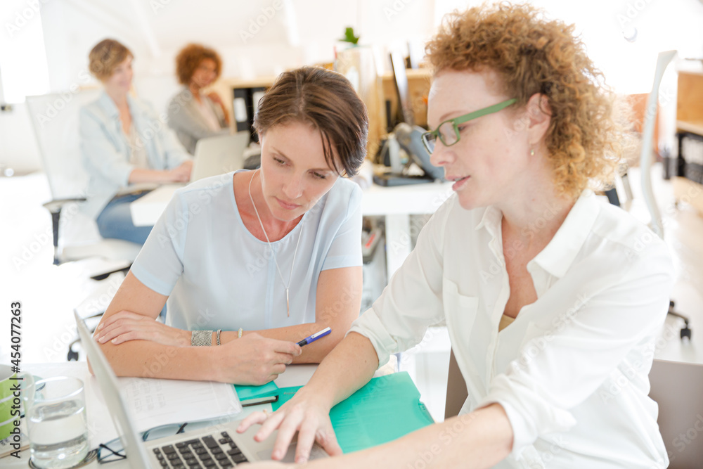 Portrait of women smiling in office with laptop on desk Portrait of women smiling in office with laptop on desk