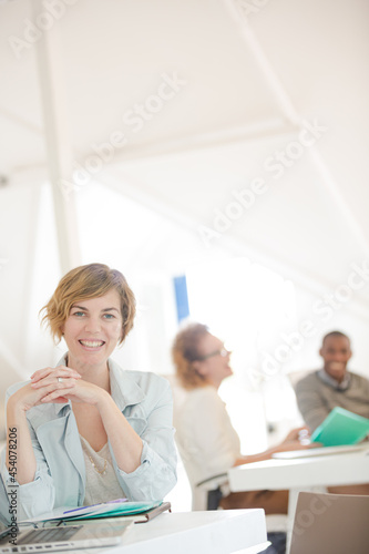Portrait of woman sitting at desk with laptop in office
