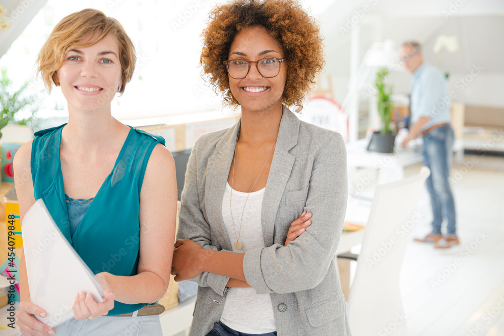 Women smiling in office, holding documents Women smiling in office, holding documents