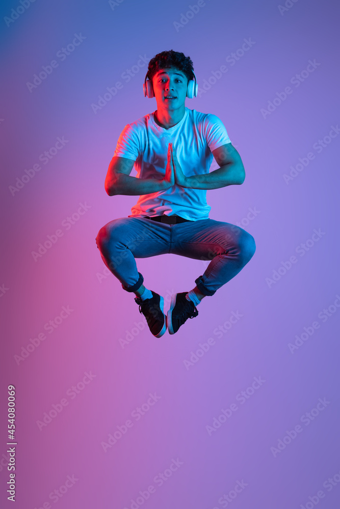 Stylish young asian man isolated over lilac color studio background in pink neon light. Concept of human emotions, fashion, beauty, youth Stylish young asian man isolated over lilac color studio background in pink neon light. Concept of human emotions, fashion, beauty, youth