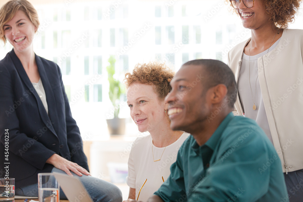 Fototapeta premium Office workers talking and smiling at desk