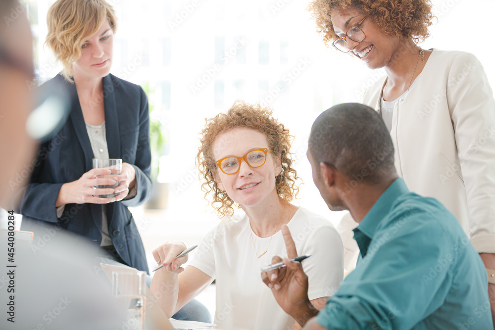 Office workers talking and smiling at meeting