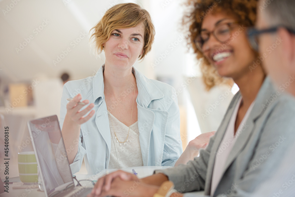 Obraz premium Three office workers talking at desk with laptop