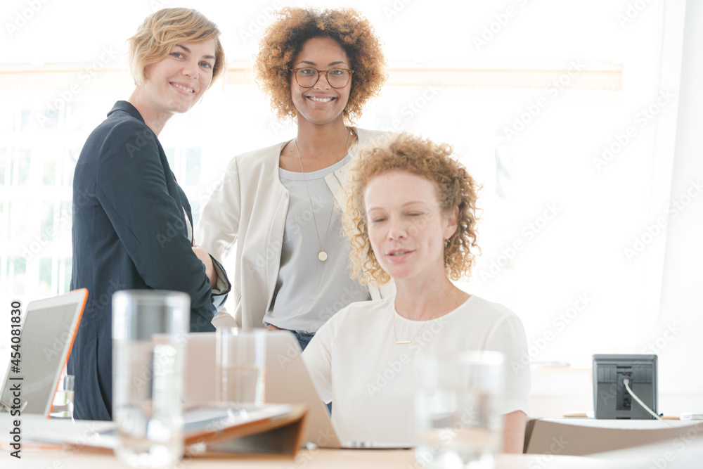 Women talking and smiling in office Women talking and smiling in office