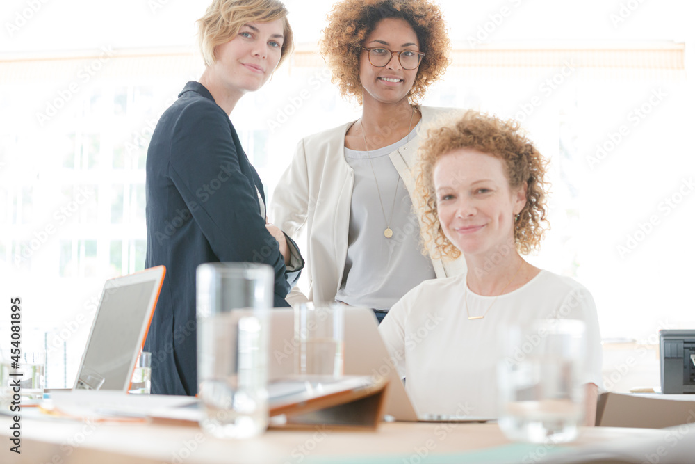 Women talking and smiling in office Women talking and smiling in office