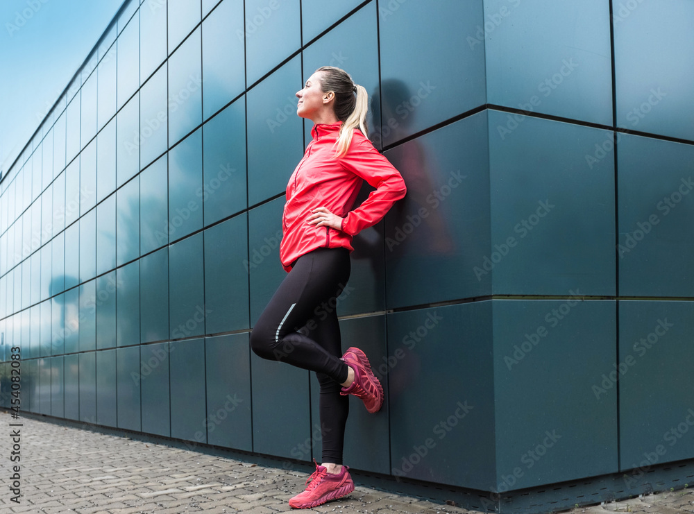 Young woman runner doing sports on sidewalk on modern background. Female model in sportswear exercising outdoors. Health concept, take care of yourself and your balance. Running outdoor.