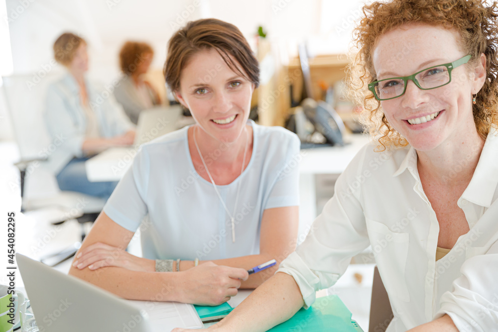 Obraz premium Portrait of women smiling in office with laptop on desk