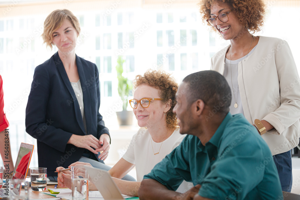 Office workers talking and smiling at desk Office workers talking and smiling at desk