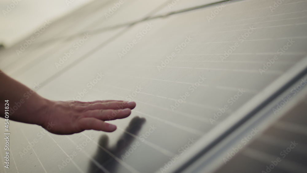 Close up of a young engineer hand is checking the operation of sun and cleanliness of photovoltaic solar panels on a sunset. Concept.renewable energy, technology, electricity, service, green, future.