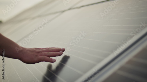 Close up of a young engineer hand is checking the operation of sun and cleanliness of photovoltaic solar panels on a sunset. Concept.renewable energy  technology  electricity  service  green  future.