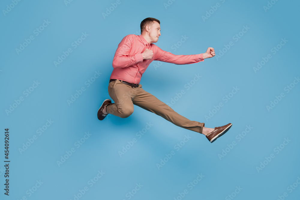 Profile portrait of sporty athletic guy jump hit fists on blue background