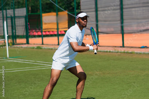 Athletic african american man playing tennis on court
