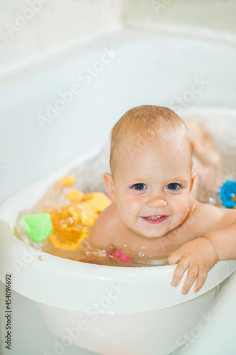 Happy toddler boy playing in bathroom close-up and copy space. Bathing babies concept...