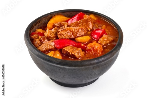 Hungarian goulash, meat stew in a rustic pot, isolated on white background.