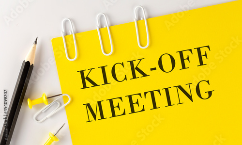 KICK-OFF MEETING word on the yellow paper with office tools on the white background