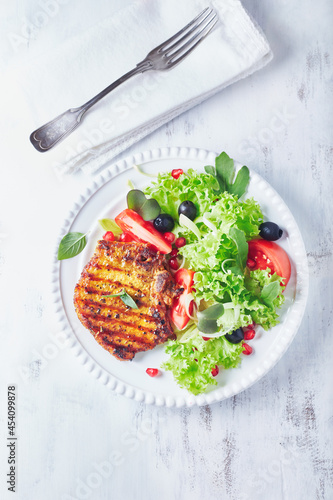 Grilled pork steak with fresh salad. White wooden background. Top view. copy space. 