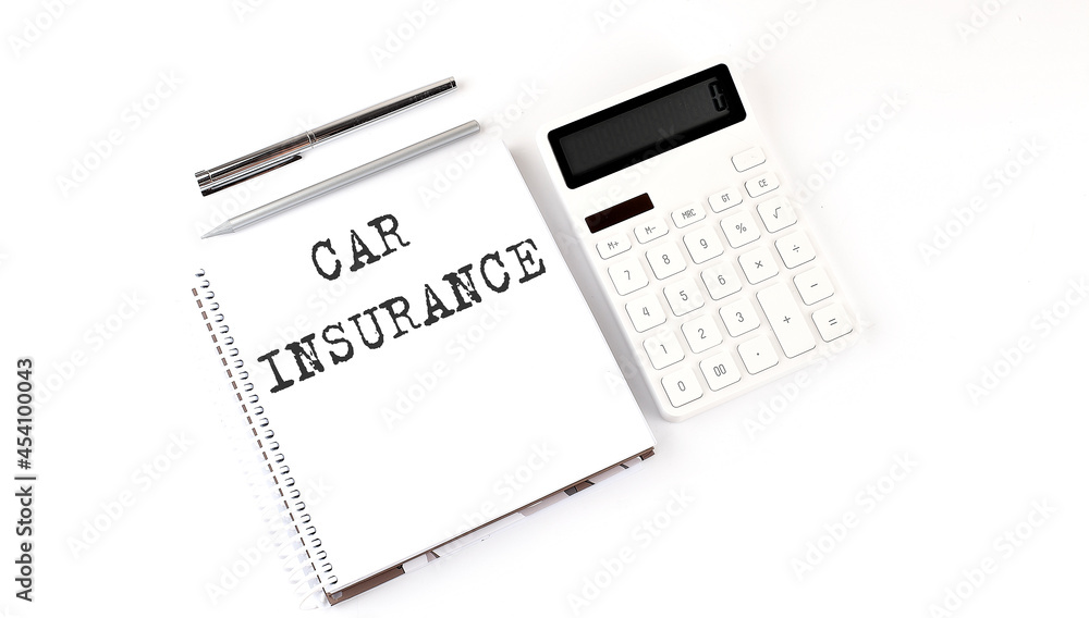 Notepad with text CAR INSURANCE with calculator and pen. White background. Business concept Notepad with text CAR INSURANCE with calculator and pen. White background. Business concept