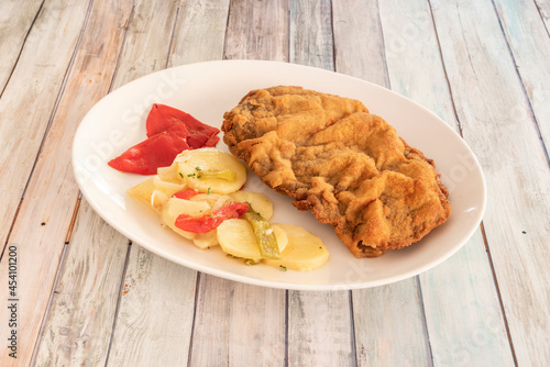 Popular Spanish cachopo recipe. Beef sirloin with ham and cheese battered with breadcrumbs, flour and egg, fried in oil and garnished with roasted potatoes with peppers photo