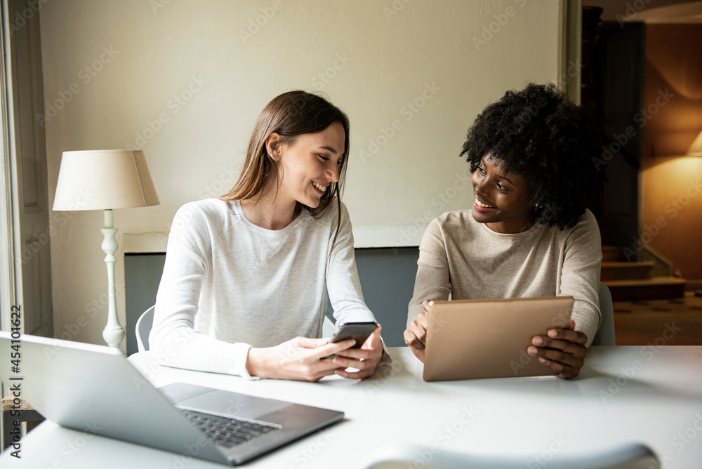 Smiling young women using digital tablet and smart phone at home Smiling young women using digital tablet and smart phone at home
