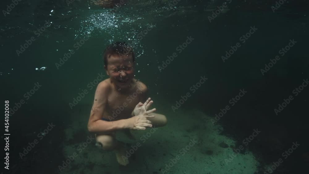 Boy dives underwater. Preteen boy has fun in the lake and dives ...