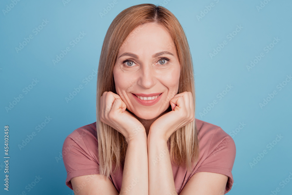 Closeup photo of attractive young woman arms hold chin smiling overjoyed isolated blue color background Closeup photo of attractive young woman arms hold chin smiling overjoyed isolated blue color background