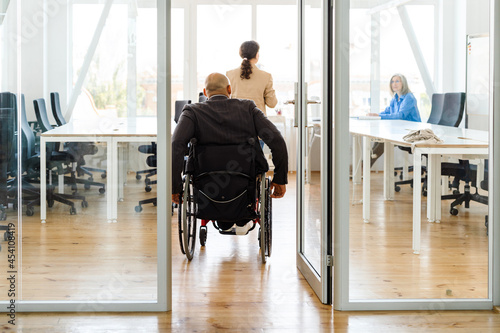 Man wearing jacket riding in wheelchair at office