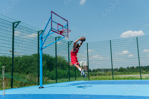 African american player jumping with basketball ball under hoop