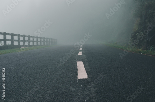 Pathway of a high mountain in a dense fog. Mist in the road by clouds in the rainy season