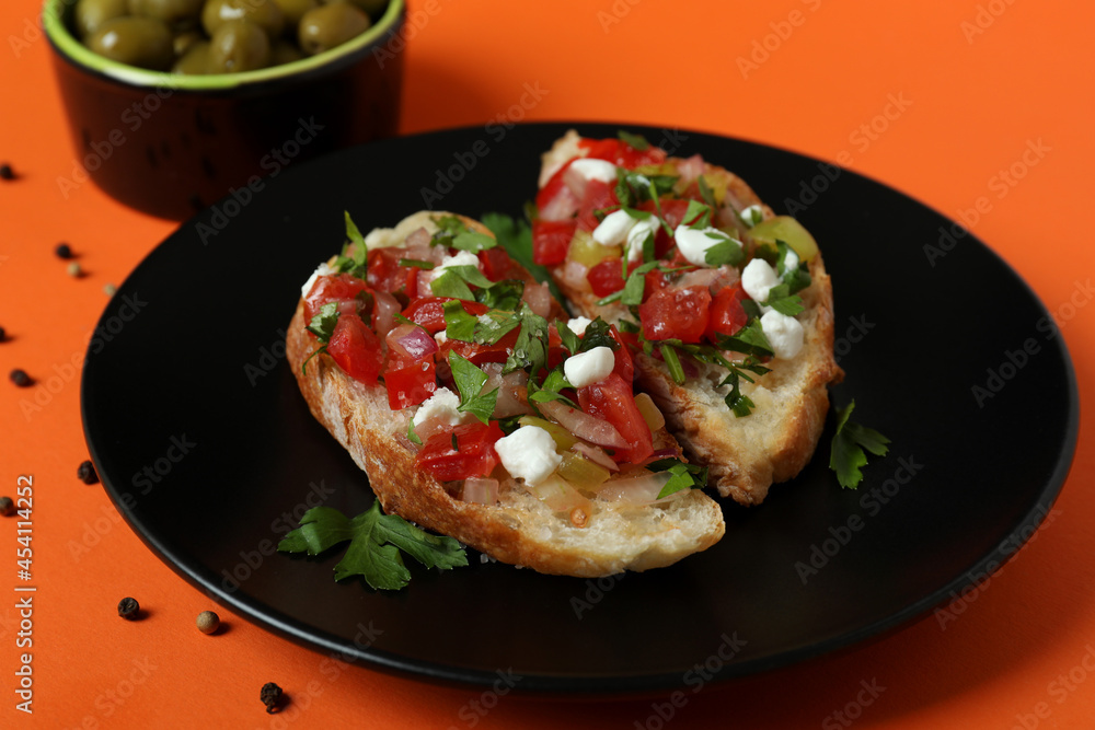 Delicious italian snacks bruschetta and ingredients on orange background Delicious italian snacks bruschetta and ingredients on orange background