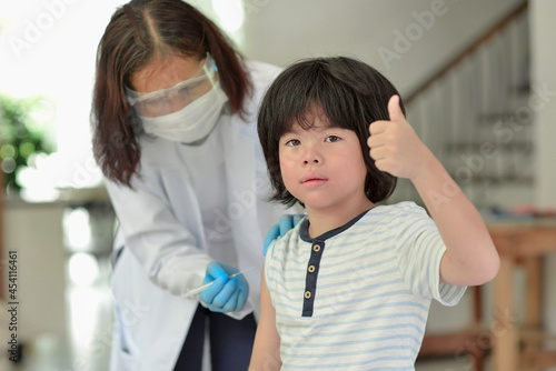 Asian child being vaccinated.Children vaccination by nurse.Medical doctor vaccinating school student in the arm.Paediatrician injecting vaccine to students in clinic.Boy thumb up.