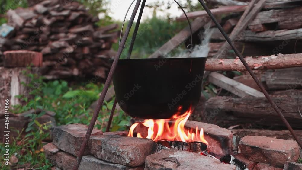 Black pot with food hanging over the fire close-up, cooking soup outdoors on the trip. Black pot with food hanging over the fire close-up, cooking soup outdoors on the trip.
