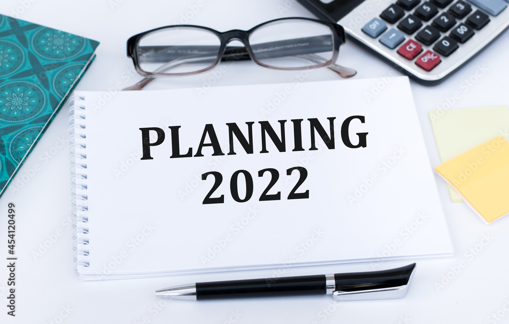 Planning 2022 text on a notebook on the table next to a black pen, glasses, calculator. Plans for the new year Planning 2022 text on a notebook on the table next to a black pen, glasses, calculator. Plans for the new year
