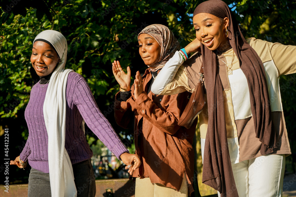 Three happy women wearing hijabs in park