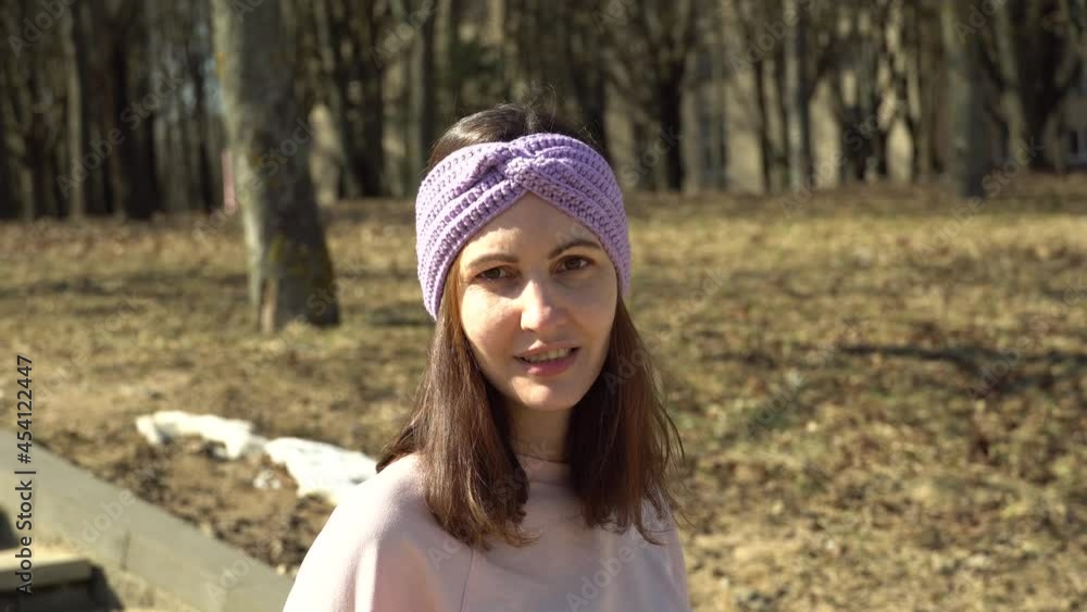 A girl in a knitted turban talks about yarn and needlework and smiling A girl in a knitted turban talks about yarn and needlework and smiling