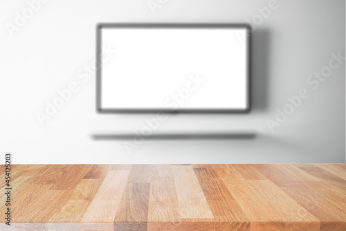 empty wooden table top with tv in living room blurred background. © Phuangphet