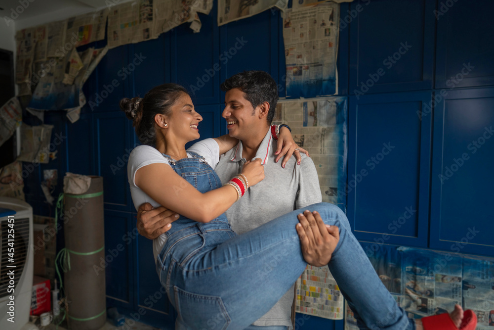 Young newlyweds sharing a romantic moment with the husband holding wife in arms. Young newlyweds sharing a romantic moment with the husband holding wife in arms.