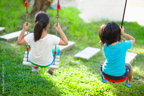 Asian children swinging in the playground.Kids sitting on swings.Boy and girl active lifestyle.Preschoolers playing in the school park.Healthy lifestyle.Childhood outdoor activity.Playful leisure. photo