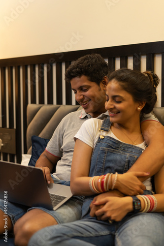 Young newlyweds seated cozily while shopping online on laptop. photo