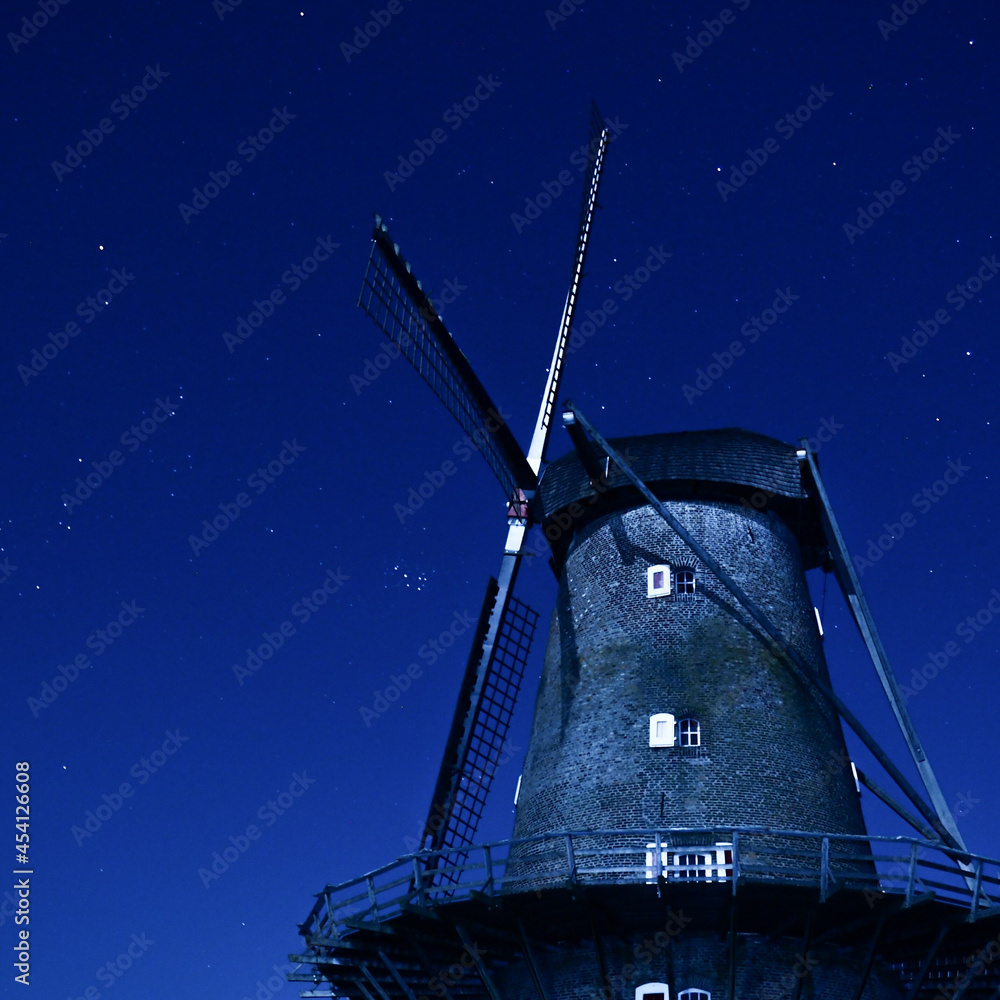 Scenic view of an old windmill on a dark stary stary - obrazy, fototapety, plakaty 