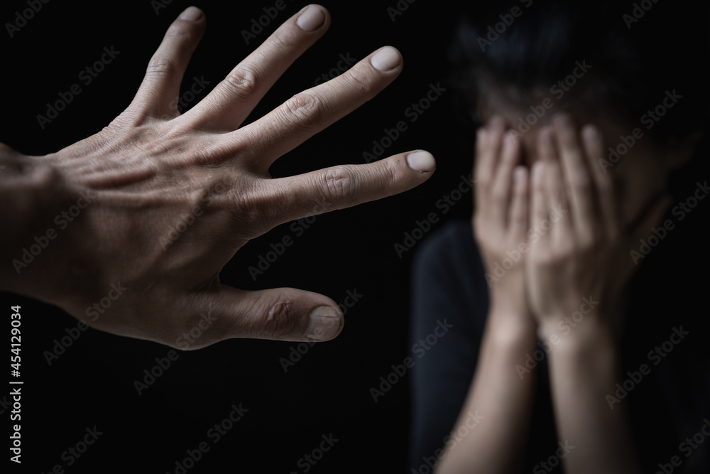 Fototapeta premium Men's hands will hurt women. Women bow their heads and cover their hands. Concept of sexual harassment, human trafficking, family rape. Harassment to the defenseless. International Women's Day.
