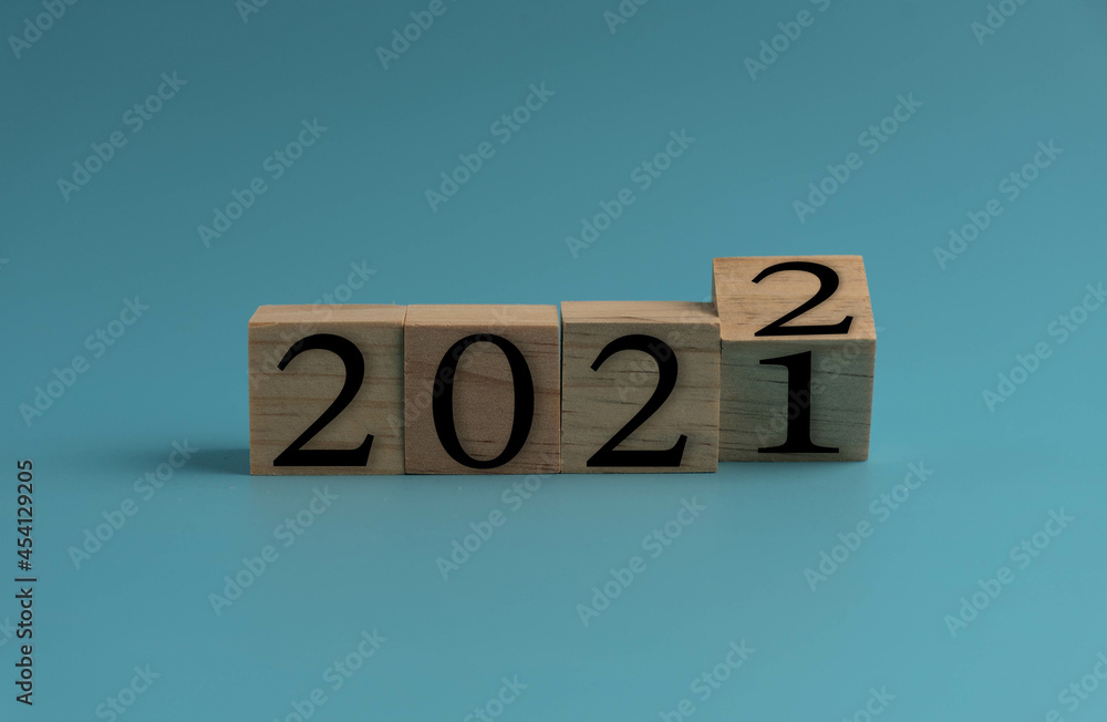 Wooden cube with word 2021 change to 2022. New Year concept on blue background. Closeup and copy space on top and under for design or text. Wooden cube with word 2021 change to 2022. New Year concept on blue background. Closeup and copy space on top and under for design or text.
